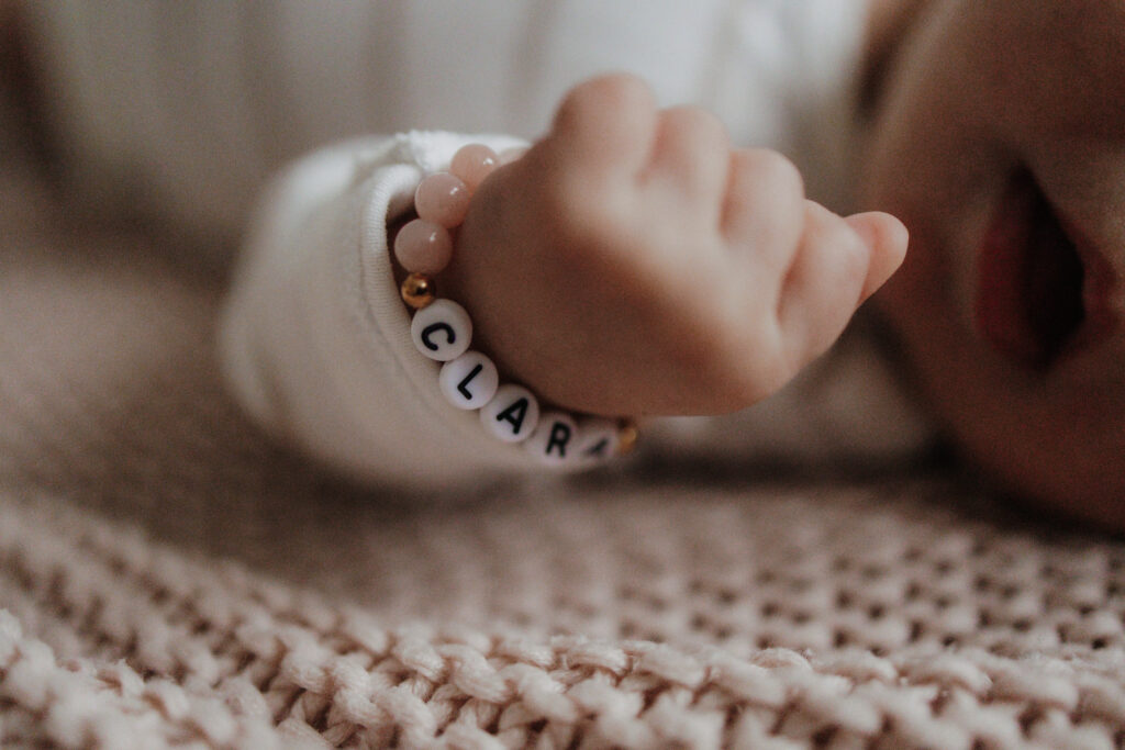 Kleine Kinderhand eines Neugeborenen mit Armband.