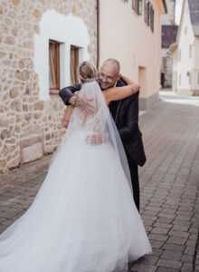 Braut umarmt Ihren Vater beim First Look im Brautkleid.